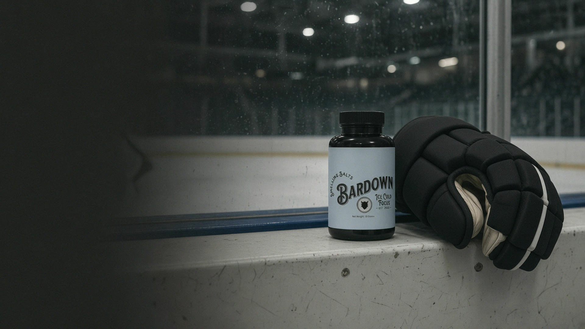 A Bardown bottle on the rink boards next to a leather hockey glove